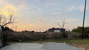 A gravel parking area with a building in the background.