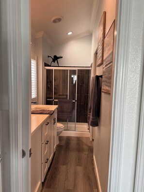 A narrow hallway leading to a bathroom with a shower, a toilet, and a sink. - 2-bedroom tiny home with 2 rv spots available Hawley (Hawley)