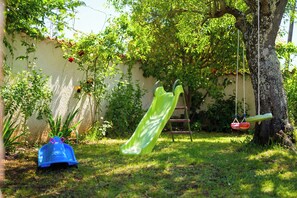 A backyard with a slide, a swing set, and a tree. - Villa Ester (Istria - Loborika) (Loborika)