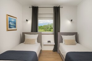 A room with two beds, a window with curtains, a small bedside table with a plant, and a framed picture on the wall. - Villa Ester (Istria - Loborika) (Loborika)