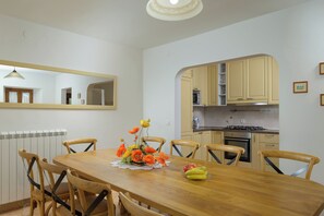 A dining area with a wooden table, chairs, a vase with flowers, and a fruit bowl. - Villa Marija Pekici (Istria - Svetvinčenat) (Svetvinčenat)
