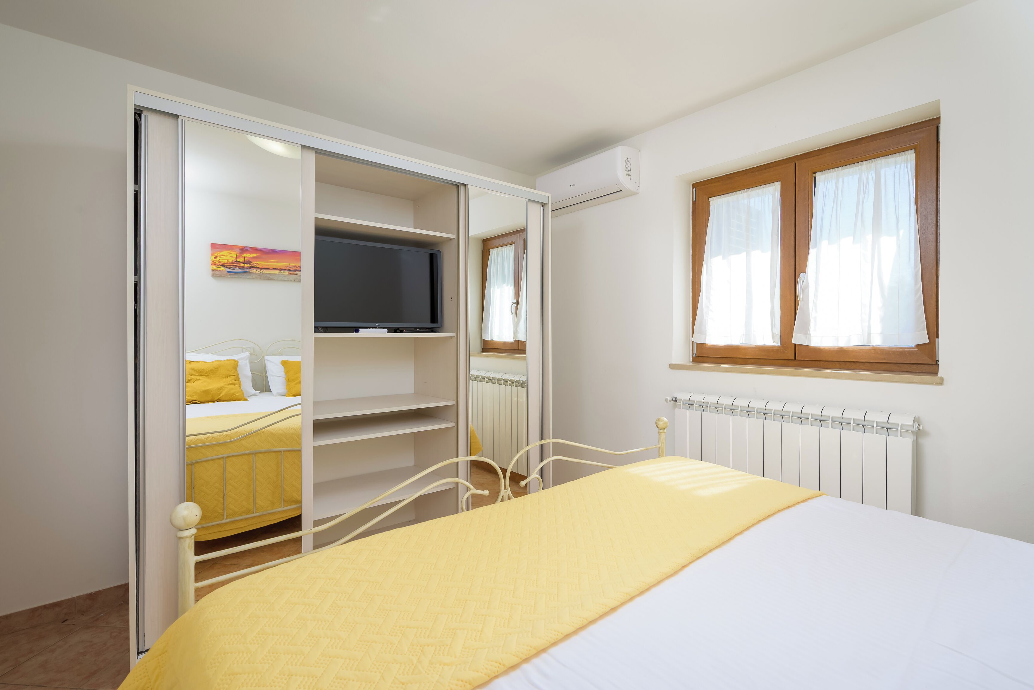 A bedroom with a bed, a wardrobe, a television, and a window.