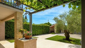 Ett takförsett utomhusområde med en pergola, en stodenpelare och en krukväxt med blommor.