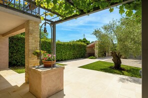 A covered outdoor area with a pergola, a stone column, and a potted plant with flowers. - Villa Marija Pekici (Istria - Svetvinčenat) (Svetvinčenat)