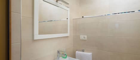 A bathroom with a white sink, a mirror, and a towel rack.