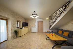 A living room with a sofa, a wooden coffee table, and a TV. There is a staircase with a railing leading to an upper level. - Villa Marija Pekici (Istria - Svetvinčenat) (Svetvinčenat)