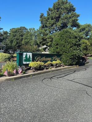 A sign for 'Bethany Pines' with a bicycle lane and American flags. - Walk to the Beach and Boardwalk, Sleeps 13, Pool: Newly Renovated (Bethany Beach)