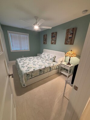 A bedroom with a bed, a nightstand, a lamp, a ceiling fan, and artwork on the wall. - Walk to the Beach and Boardwalk, Sleeps 13, Pool: Newly Renovated (Bethany Beach)