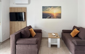 A modern living room with two sofas, a small table, a TV, and a sunset painting on the wall. - Awesome apartment in Opric (Opric)