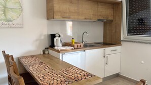 A kitchen with wooden cabinets, a countertop, a sink, a coffee maker, and a dining table with a unique wood pattern. - Awesome apartment in Opric (Opric)