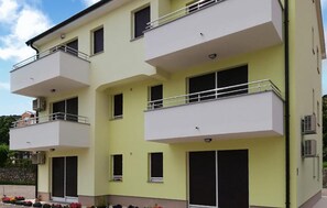 A multi-story residential building with balconies, air conditioning units, and a clear sky. - Awesome apartment in Opric (Opric)