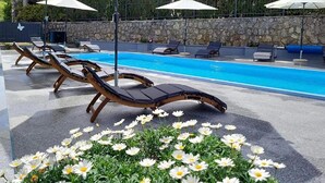 Un área junto a la piscina con sillas de descanso y un parterre de flores.