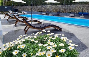 Ein Poolbereich mit Liegestühlen und einer Blumenbeetanlage.