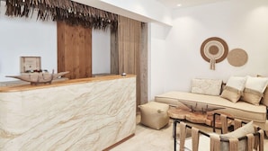 Een modern interieur met een marmeren receptiebalie, een zithoek en een eethoek met stoelen en een tafel.