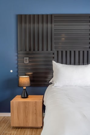 Ein Schlafzimmer mit einem Bett, einem Nachttisch mit Lampe und einem modernen Kopfteil.