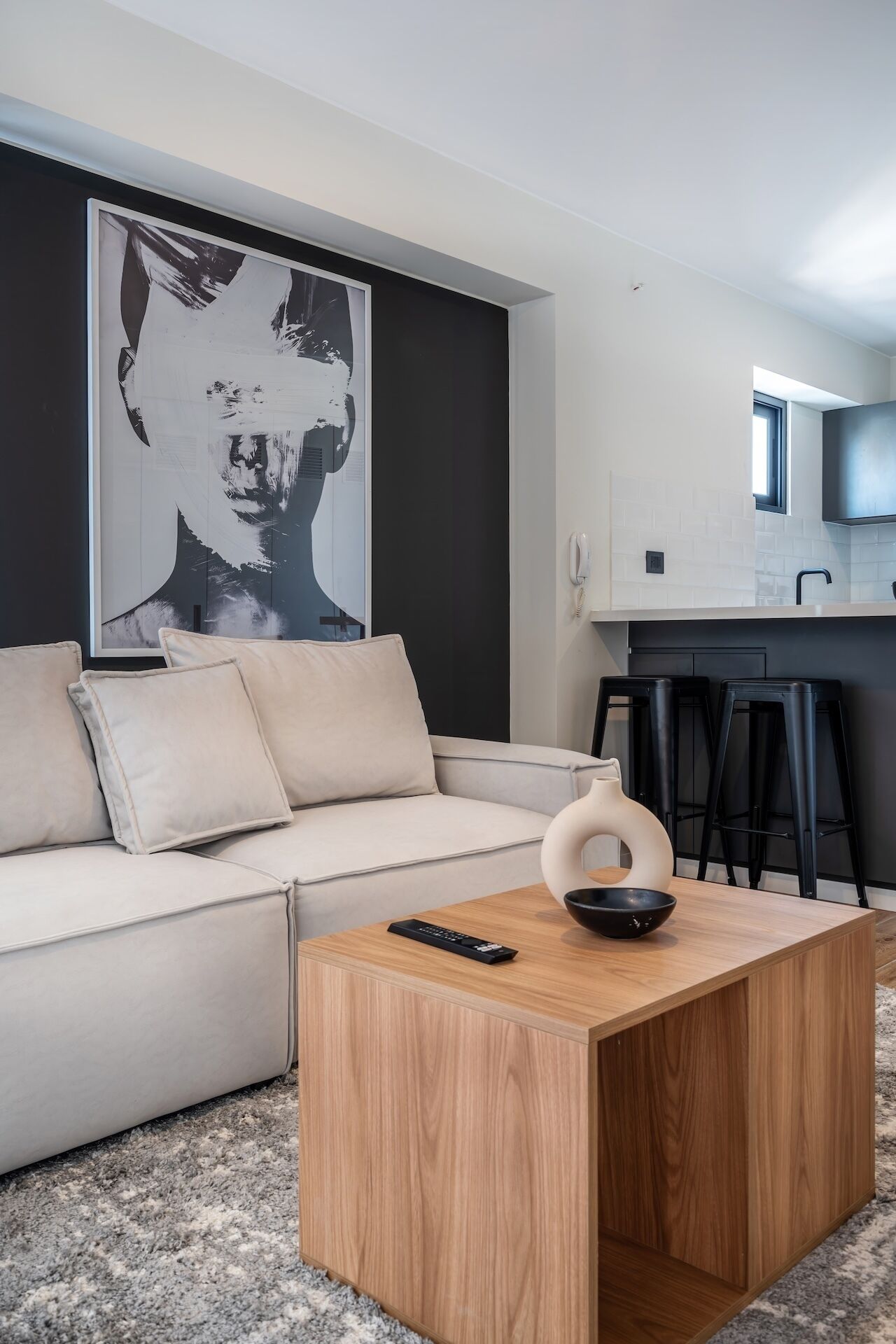 A modern living room with a sofa, a coffee table, a remote control, and a black bowl.