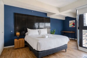 A modern bedroom with a large bed, a bedside table, a desk, and a window. - San Isidro Lux Studio Apartment (San Isidro)