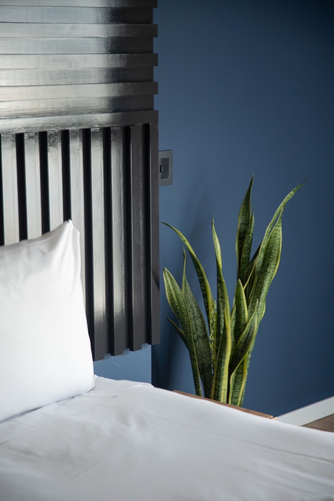 A bed with a white pillow and a headboard with vertical slats.