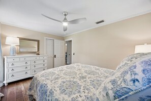 A bedroom with a bed, dresser, ceiling fan, and a door leading to another room. - Waterfront Amelia Island home with amazing views, deck, parking. (Fernandina Beach)
