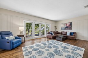 A living room with a blue sofa, a brown sofa, a coffee table, a patterned rug, and a painting on the wall. - Waterfront Amelia Island home with amazing views, deck, parking. (Fernandina Beach)