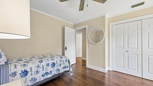 Une chambre à coucher avec un lit, un ventilateur de plafond, une porte et un couloir.