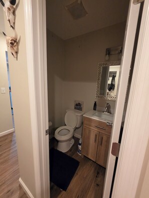 Ein Badezimmer mit Toilette, Waschbecken, Spiegel und Holzschränken.
