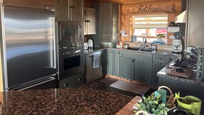 Una cocina con electrodomésticos de acero inoxidable, encimeras de granito y armarios de madera.