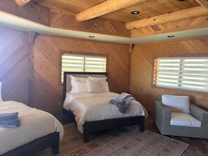 Ein Zimmer mit Holzwänden, einem Bett, zwei Nachttischen und einem Sessel.
