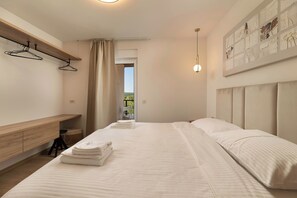 A hotel room with a bed, a desk, a chair, a hanging coat rack, and a window with a view. - Villa Azoria with pool and jacuzzi (Kvarner - Žgaljići) (Žgaljići)
