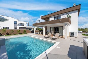 A modern two-story house with a swimming pool, outdoor seating, and a visible air conditioning unit. - Villa Azoria with pool and jacuzzi (Kvarner - Žgaljići) (Žgaljići)