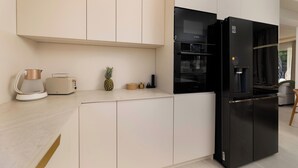 Et moderne køkken med et sort køleskab, kaffemaskine og brødrister på bordet.