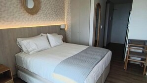 A hotel room with a large bed, a wooden nightstand, a mirror, and a wardrobe. - Santa Marta apartment ocean view 579 a (Santa marta)
