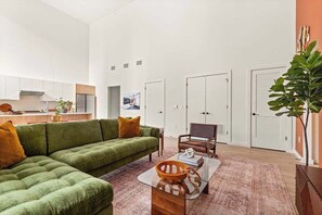 A modern living space with a sectional sofa, a coffee table, and a dining area. - Penthouse Combo | Pool, Views, Near Broadway (Nashville)