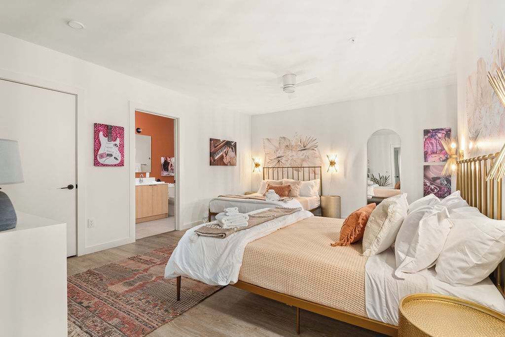 A bedroom with a bed, bedside tables, a mirror, and artwork on the walls.