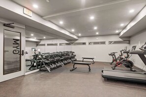 Ein Fitnessraum mit Spiegelwand, einer Bank, Kurzhanteln und Laufbändern.