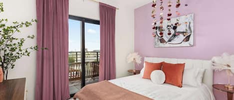 Un dormitorio con cama, cortinas, un cuadro y vistas a través de un ventanal.