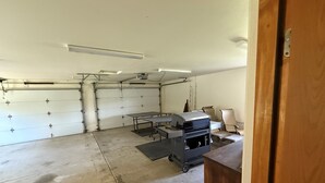 A garage with a workbench, chairs, and a ceiling-mounted projector.