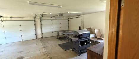 A garage with a workbench, chairs, and a ceiling-mounted projector.