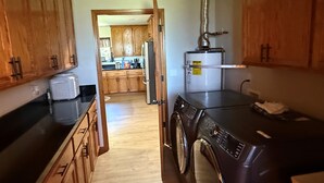 A kitchen with wooden cabinets, a refrigerator, a washing machine, and a water heater.