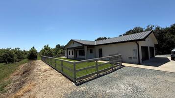 A two-story building with a fenced driveway and a gravel parking area.