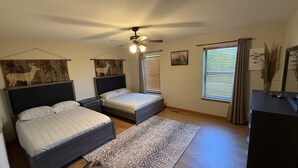 A bedroom with two beds, a ceiling fan, a window with blinds, and a rug.