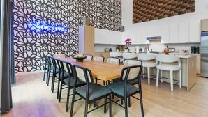 A modern kitchen with white cabinets, a stainless steel refrigerator, and a dining area with a wooden table and chairs. - The Grand Skyline | 2 Designer Condos, Pool, Gym (Nashville)