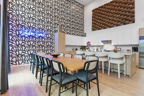 A modern kitchen with white cabinets, a stainless steel refrigerator, and a dining area with a wooden table and chairs. - The Grand Skyline | 2 Designer Condos, Pool, Gym (Nashville)