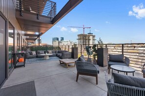 A rooftop terrace with a modern design, featuring a sofa set, a coffee table, and a dining table. - The Grand Skyline | 2 Designer Condos, Pool, Gym (Nashville)