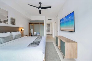Ein modernes Hotelzimmer mit einem großen Bett, einem Deckenventilator, einem Fernseher und einem Strandbild.