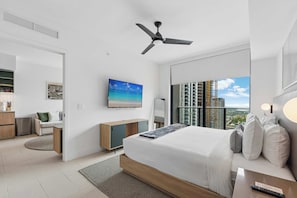 Ein modernes Hotelzimmer mit einem großen Bett, einem Schreibtisch, einem Fernseher und Blick auf die Stadt.