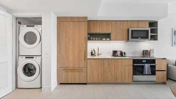 Eine moderne Küche mit integrierten Geräten, Holzschränken und einer gefliesten Spritzschutzwand.