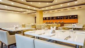 A hotel dining area with multiple tables set for guests, equipped with cutlery and glassware. - Siesta Navi Mumbai (Navi Mumbai)