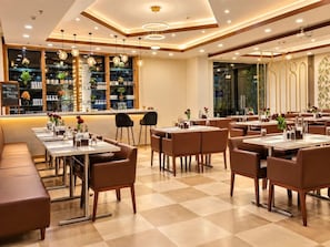 A modern restaurant interior with multiple dining tables and booths, a bar area, and a view of the city through large windows. - Siesta Navi Mumbai (Navi Mumbai)