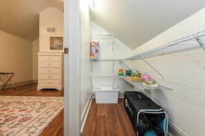 Un cuarto de juegos infantil con un aparador blanco, una estantería para guardar juguetes y un cesto pequeño blanco.